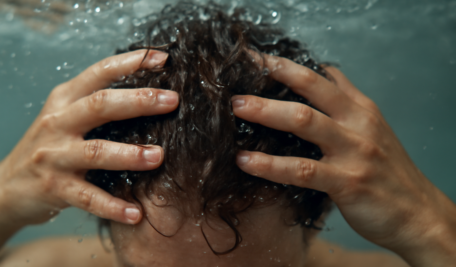 mains massant cuir chevelu sous l'eau