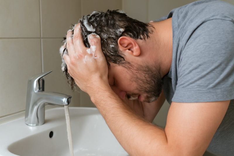 homme se lavant les cheveux au lavabo