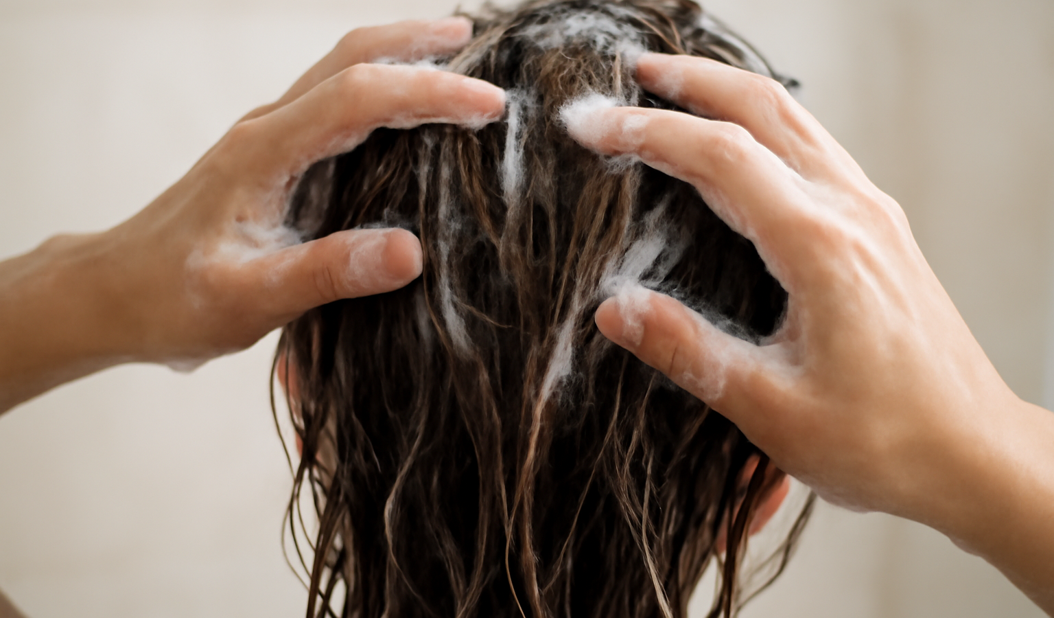 mains appliquant shampooing sur cheveux mouilles