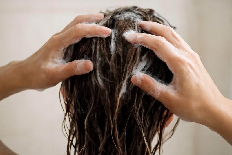 mains appliquant shampooing sur cheveux mouilles