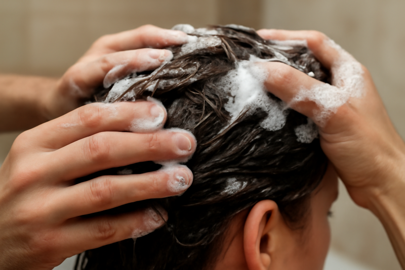 mains appliquant shampooing sur cheveux mouilles