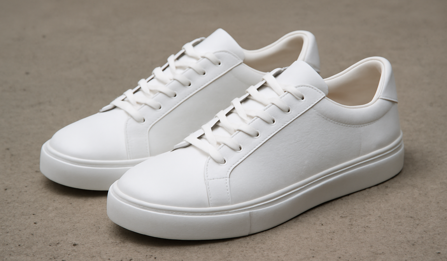 paire de sneakers blanches posees sur beton